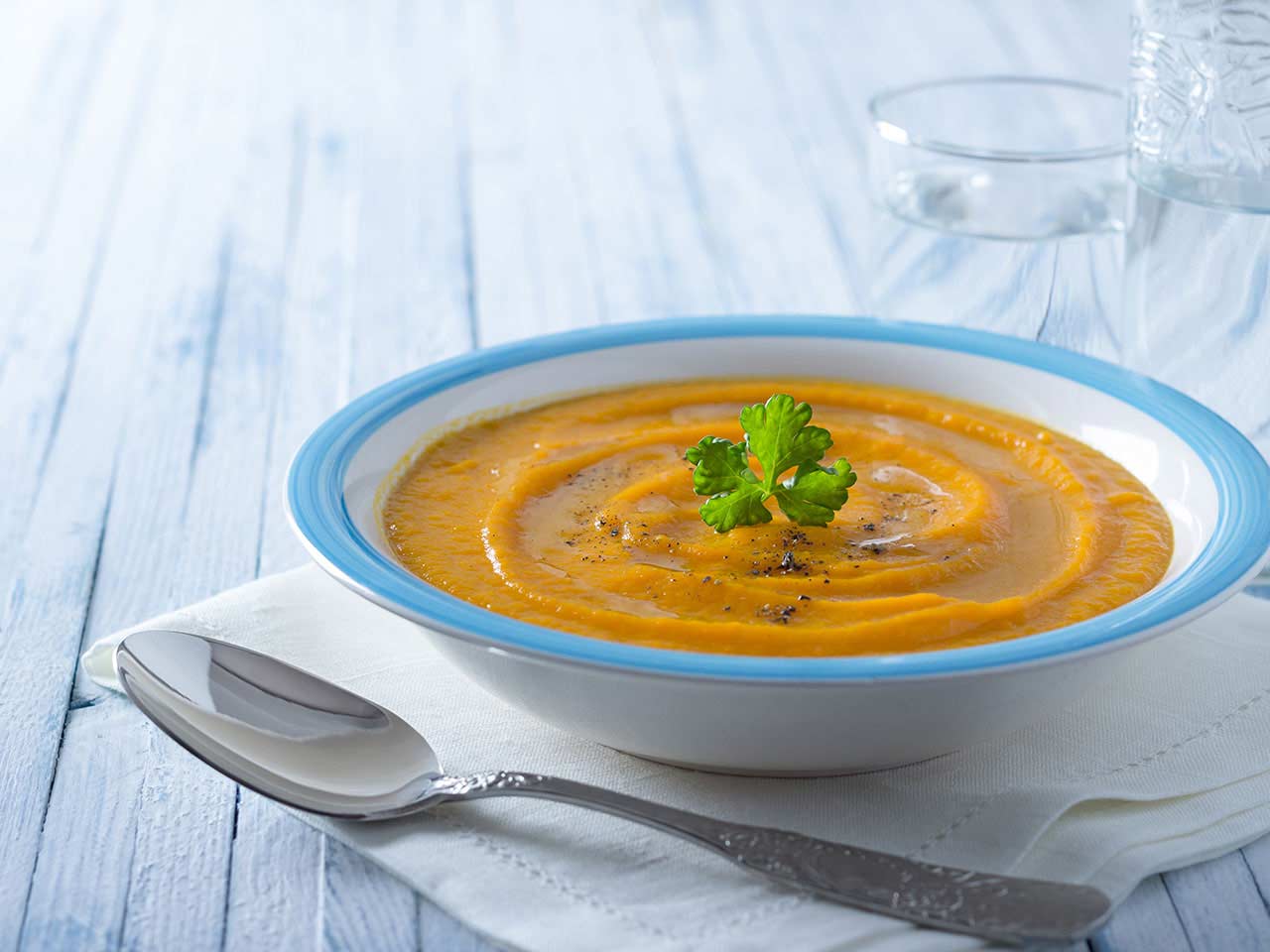 Bowl of carrot soup on wooden table