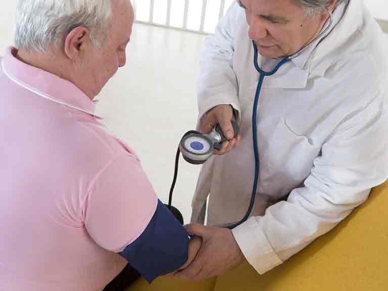 Doctor in white coat measuring blood pressure