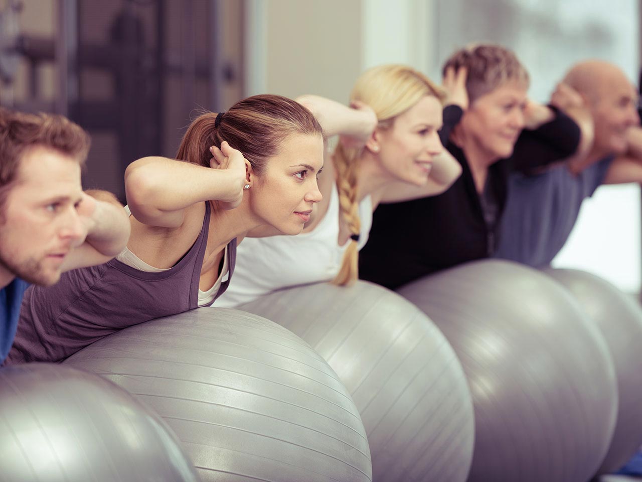 Group of people in gym using pilates balls