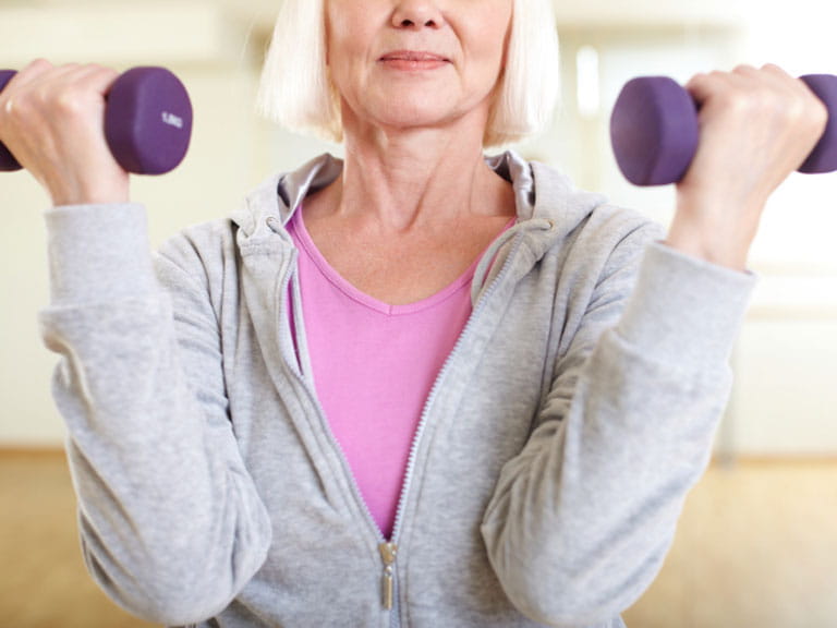 Woman lifting small weights to prevent muscle loss
