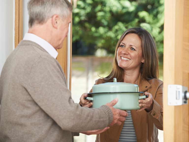 Woman bringing a home-cooked dish to a neighbour.