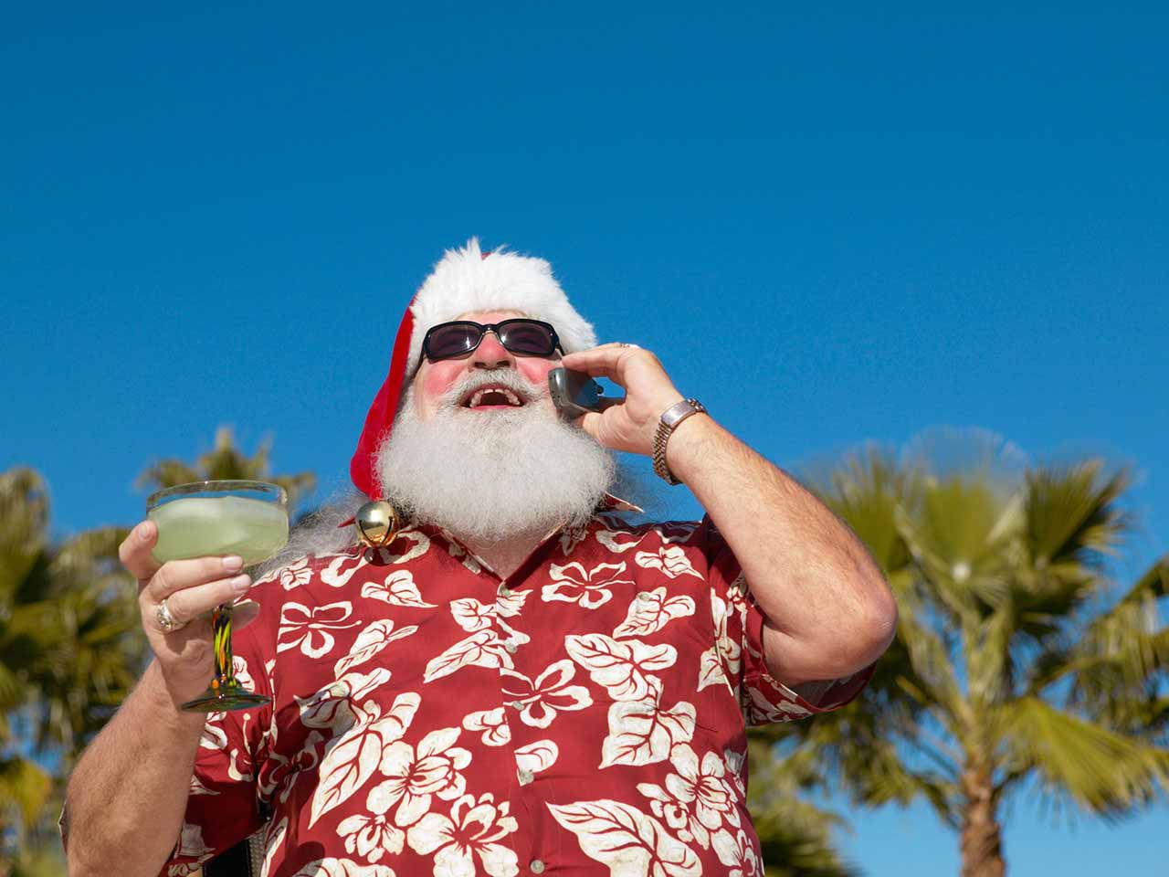 Man dressed as Father Christmas drinking a cocktail in the sun
