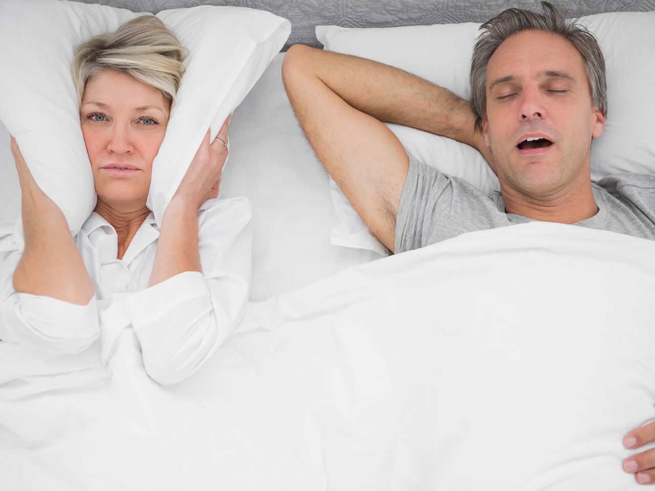 Mature couple in bed with the man snoring