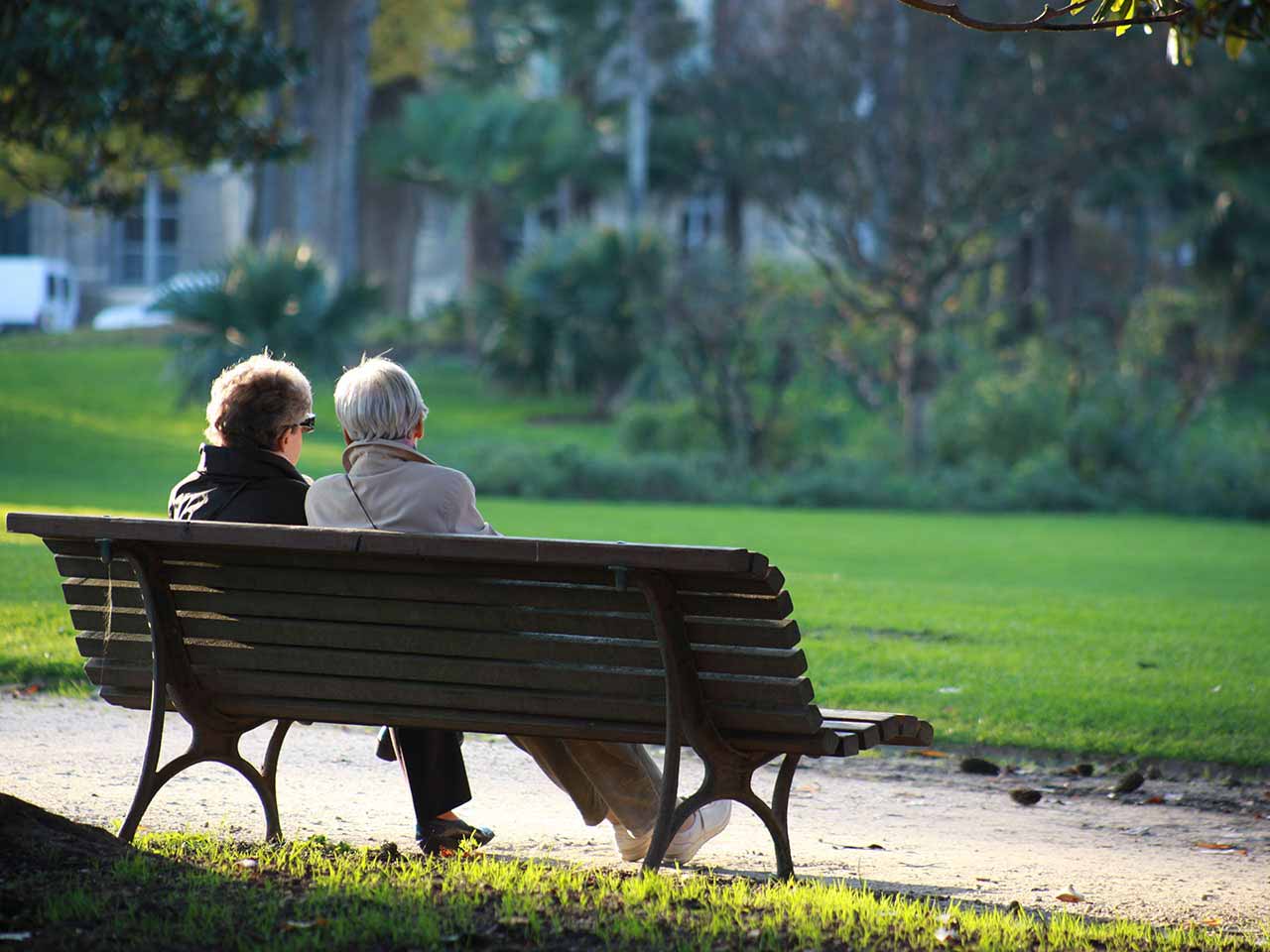 Two mature women sitting on park bench