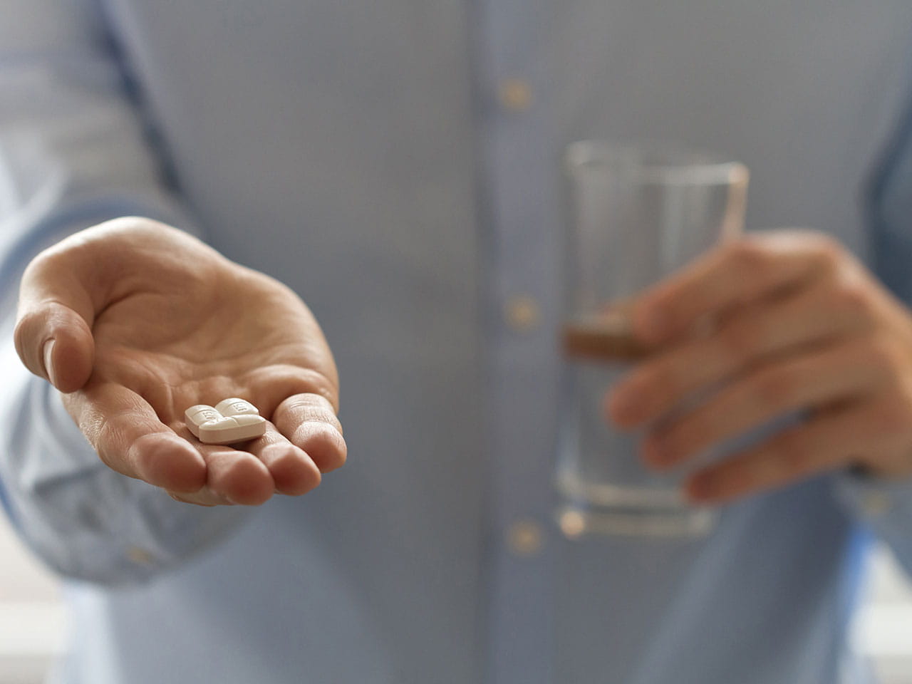 Man holding out his hand with painkillers