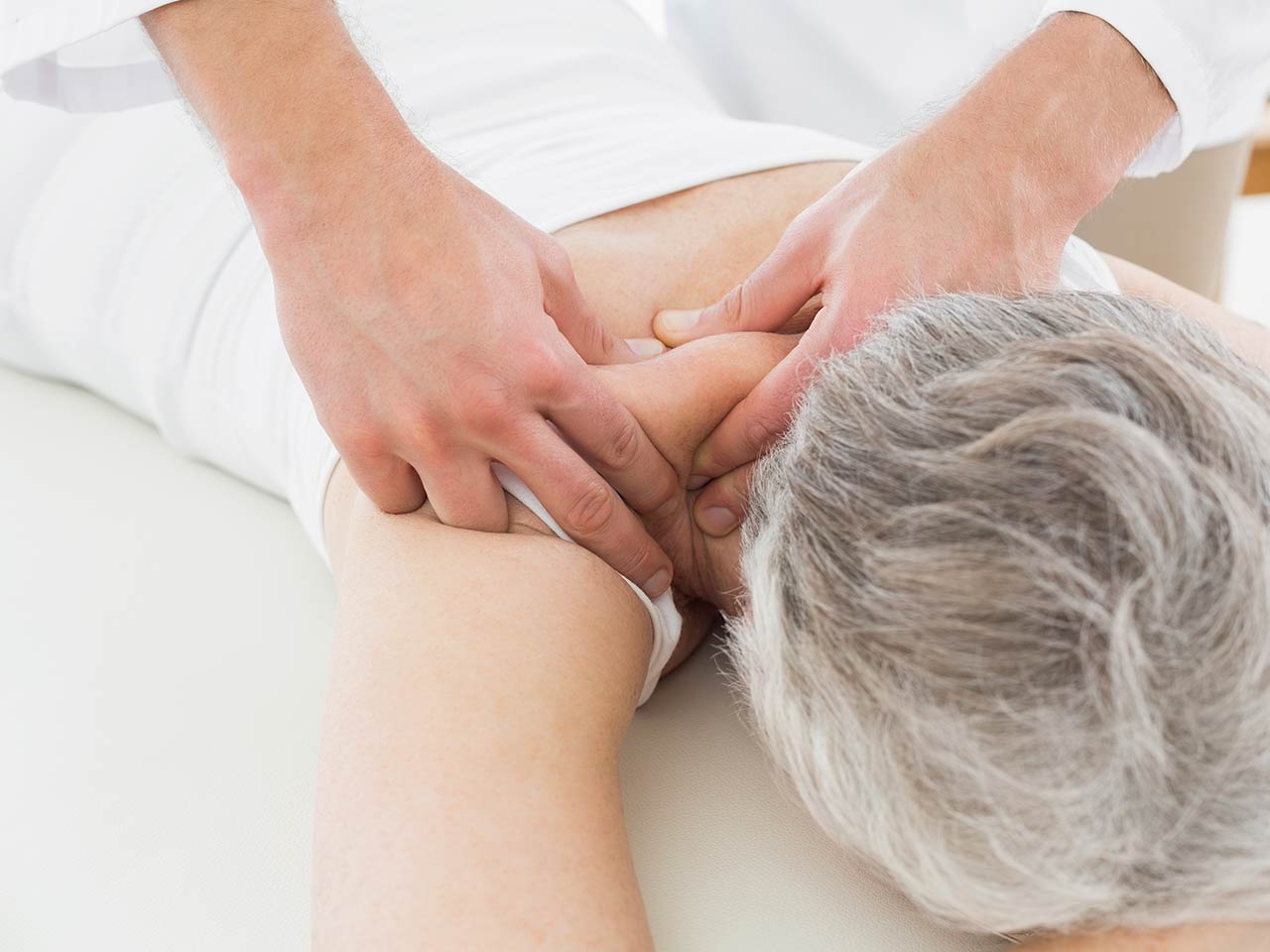 Senior receiving massage for neck pain