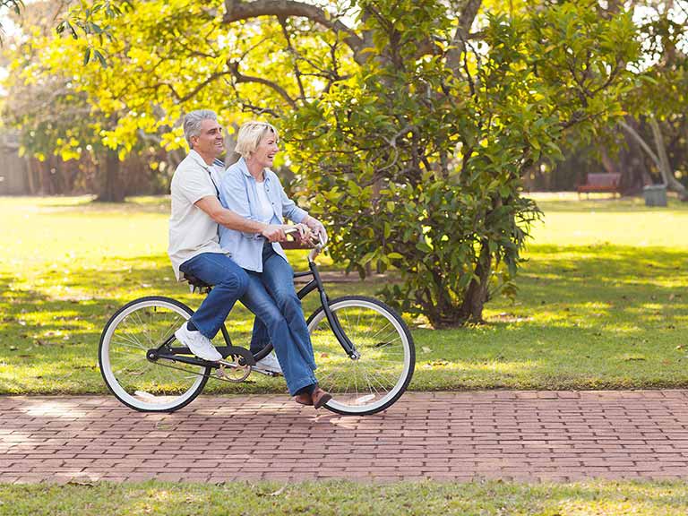 Mature couple riding on a bike outdoors having fun