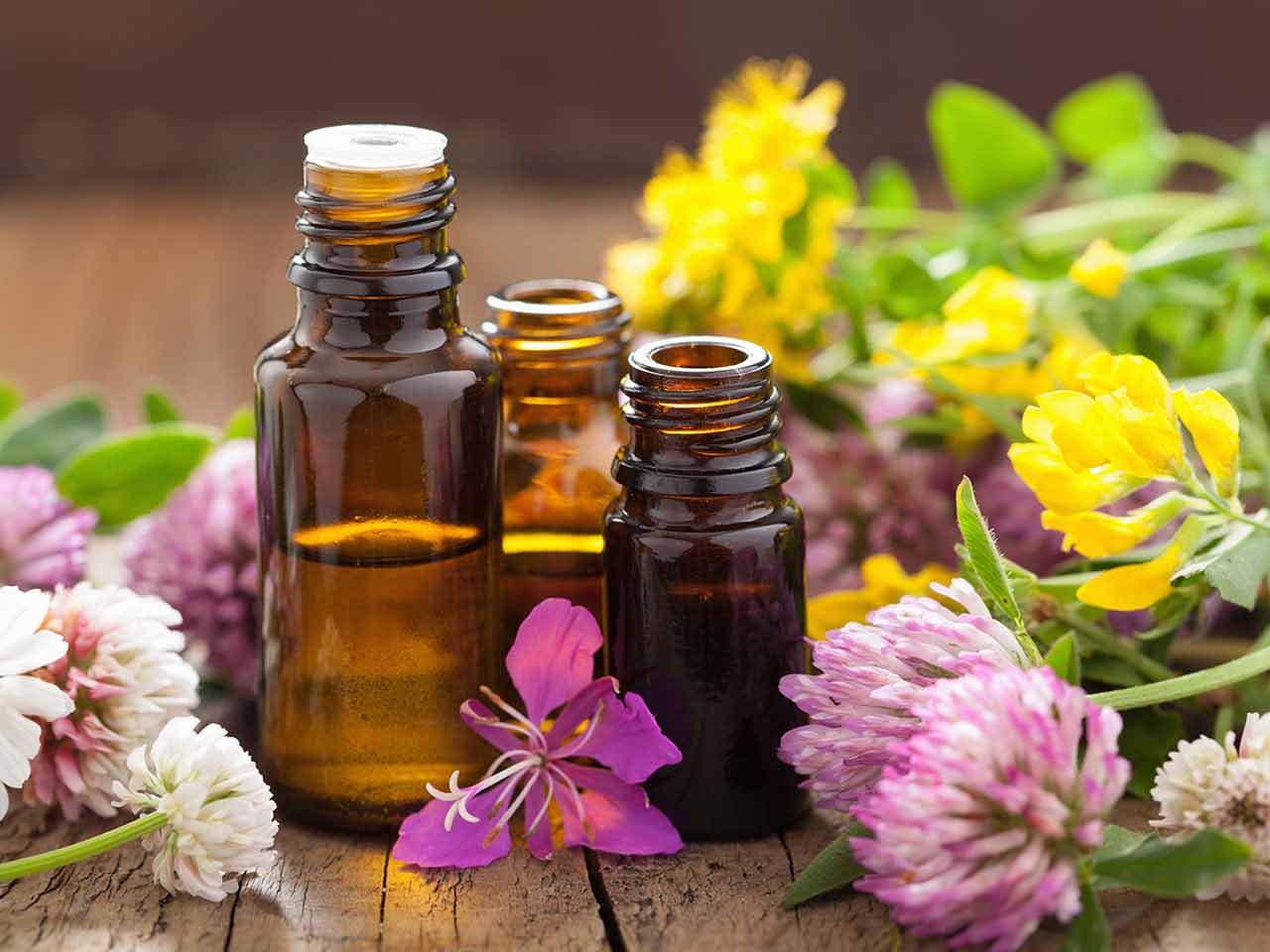 Essential oil bottles on wooden table with flowers