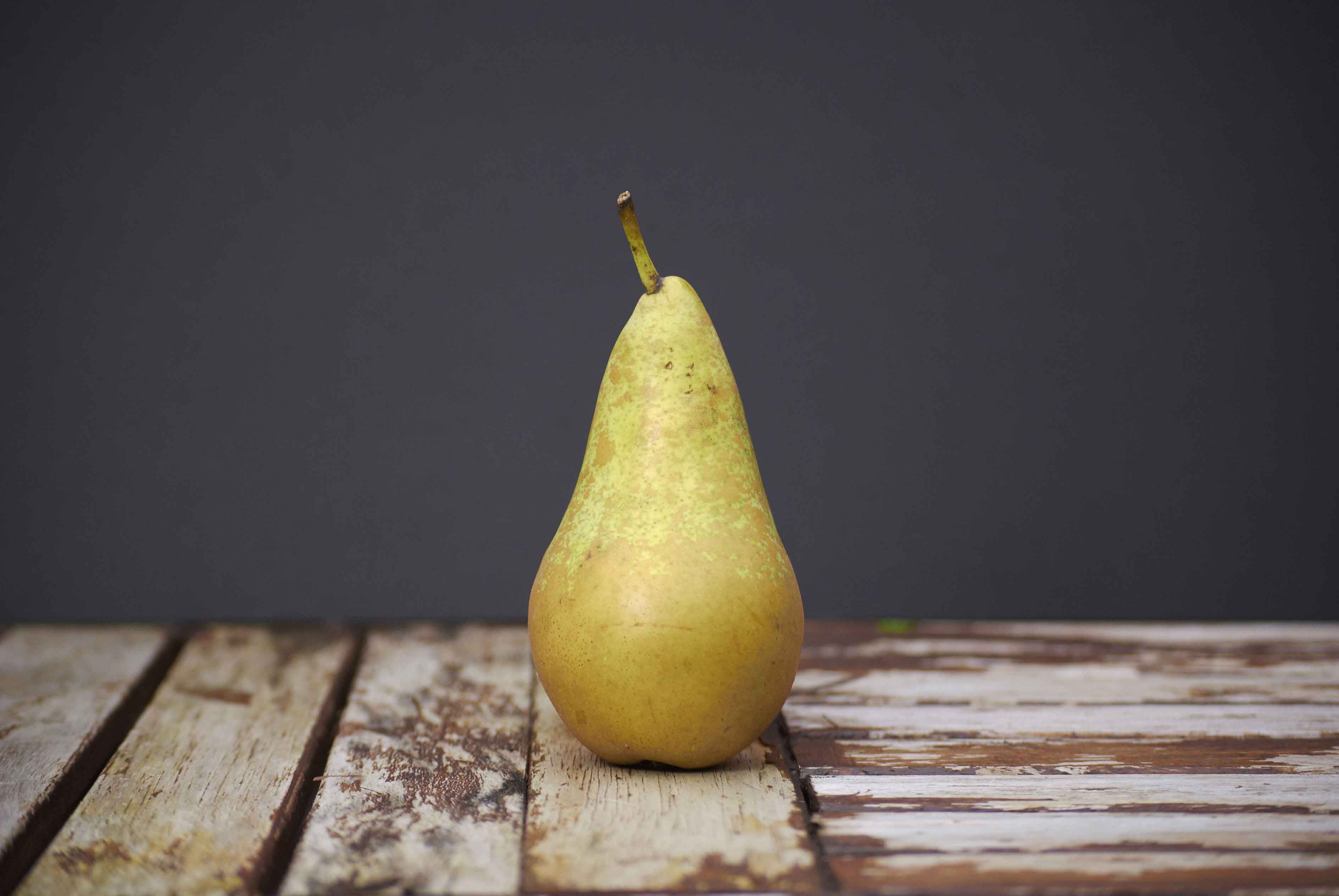 A pear sitting on a wooden board