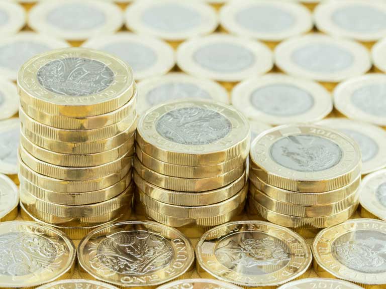 Three stacks of pound coins on a bed of pound coins