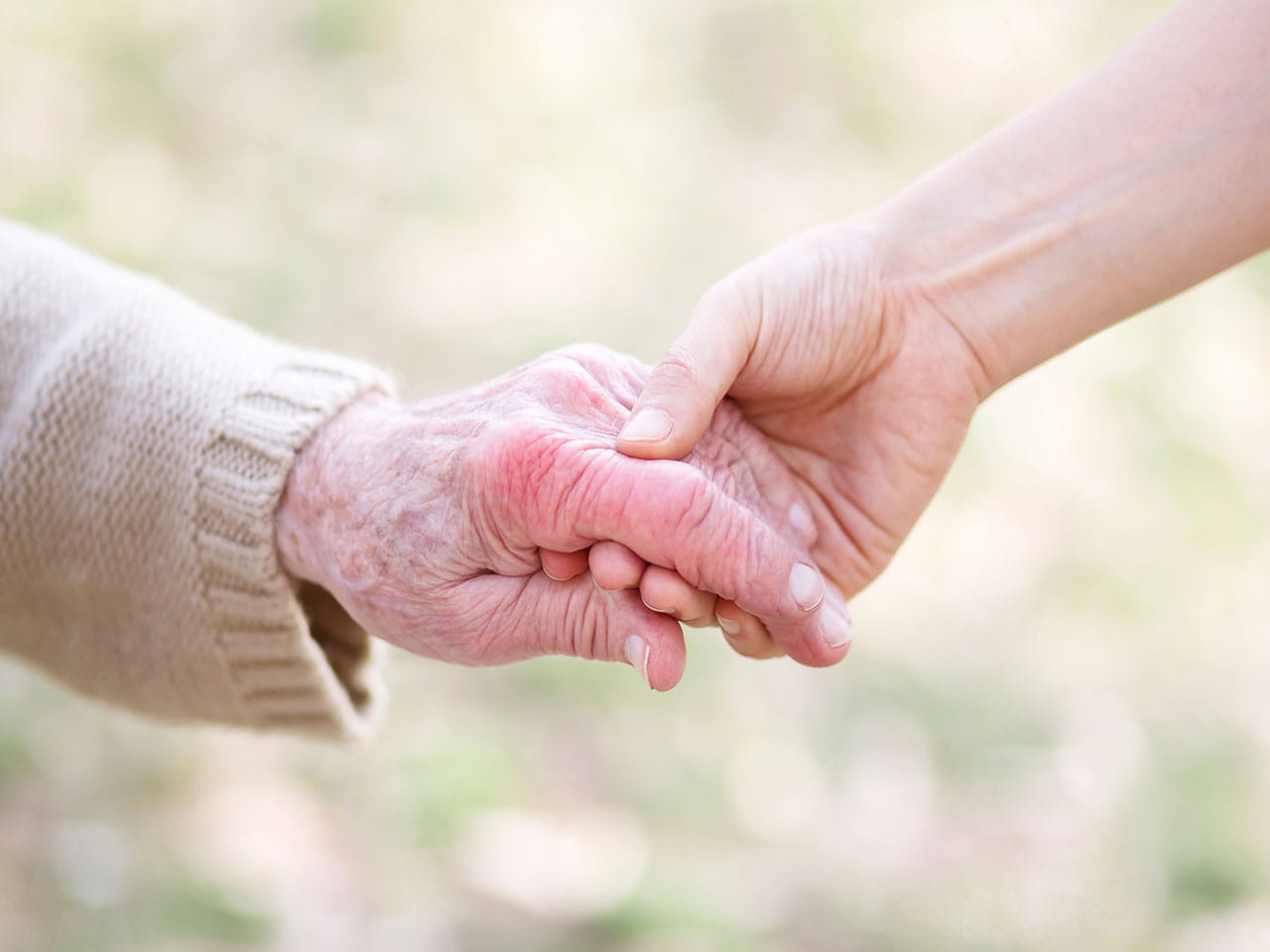 A carer holding their charge's hand to represent someone who needs to know how to claim Carer's Allowance