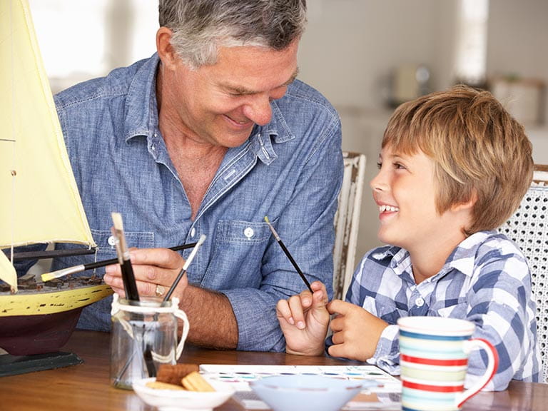 Granddad and grandson painting a toy boat