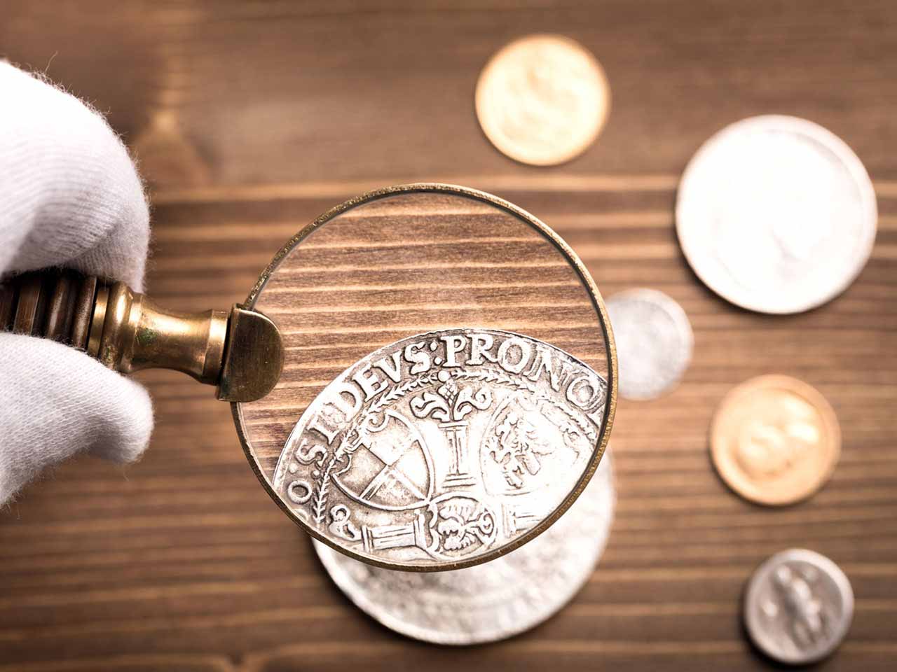 Coin valuation: Old coins through magnifying glass to represent the coins' value