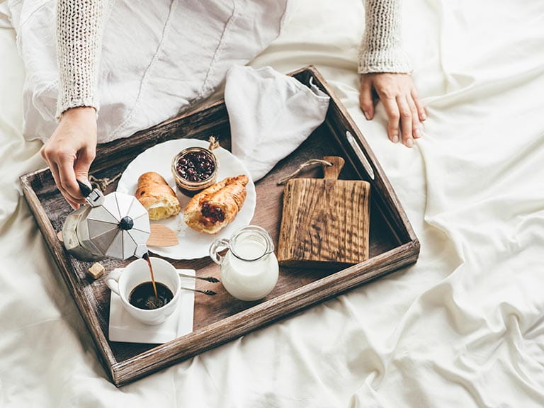 A woman enjoys breakfast in bed at a bed and breakfast