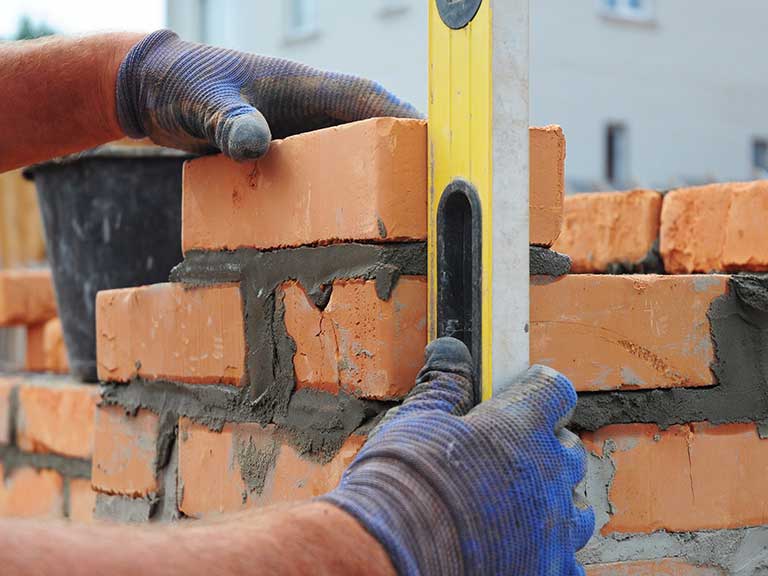 A builder builds a brick wall for a house extension