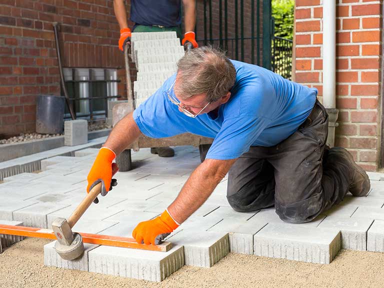 A man lays the patio slabs for his patio to cut the cost