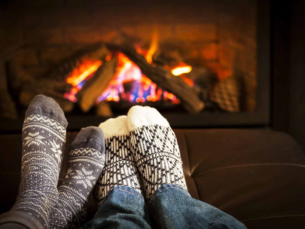 Couple's feet in socks in front of fire to represent the Winter Fuel Payment - a retirement benefit