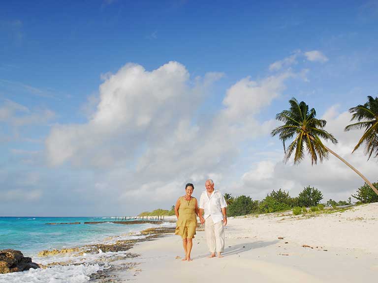 A retired couple stroll on a beach