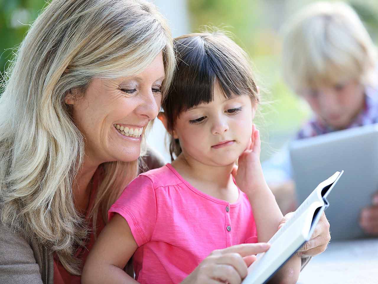 Mature lady teaching child to read