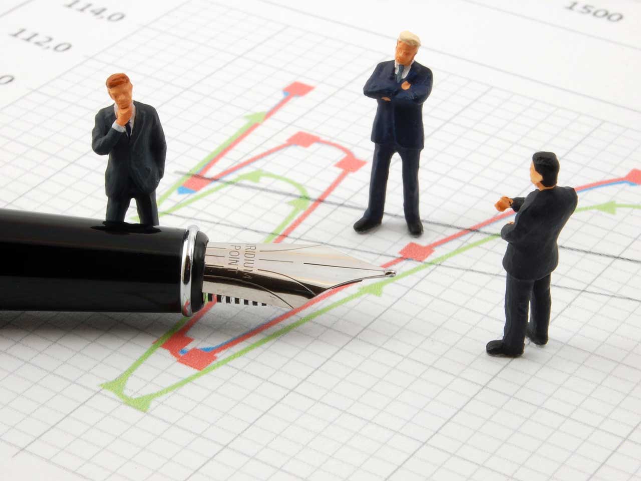 Figurines of stockbrokers looking at a stocks and shares graph