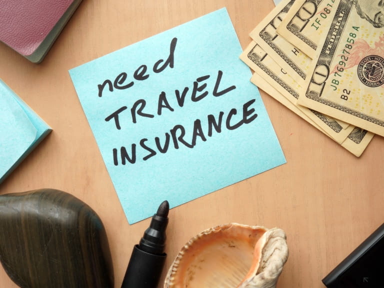 A post-it note reminder to buy travel insurance for a holiday
