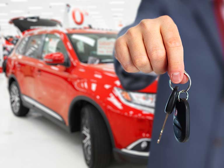 A salesman hands over the keys to a brand new car