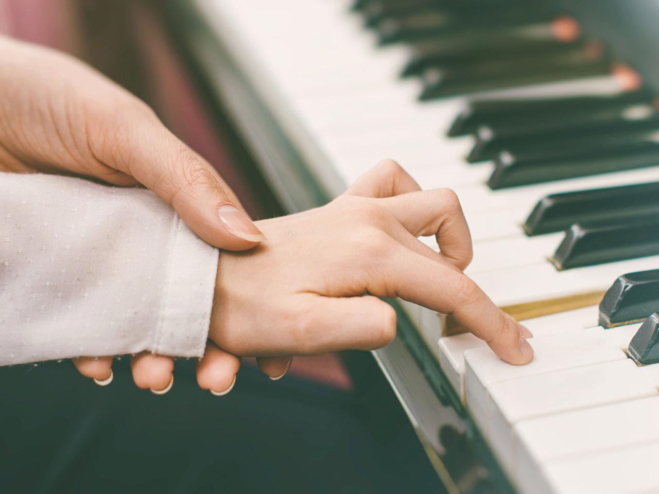 Piano teacher's hands on piano keys