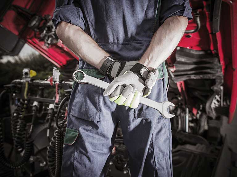 A mechanic stands holding a wrench