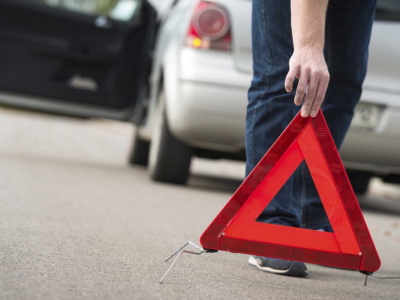 Scammer putting out a warning triangle to try to get motorists to pull over and help