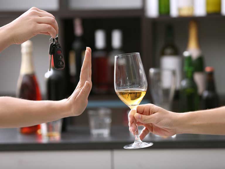 A woman refuses a glass of wine as she is driving