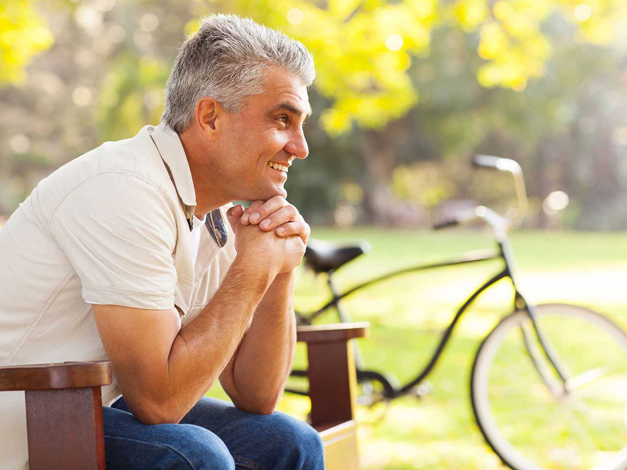 Mature man sitting on a bench smiling 