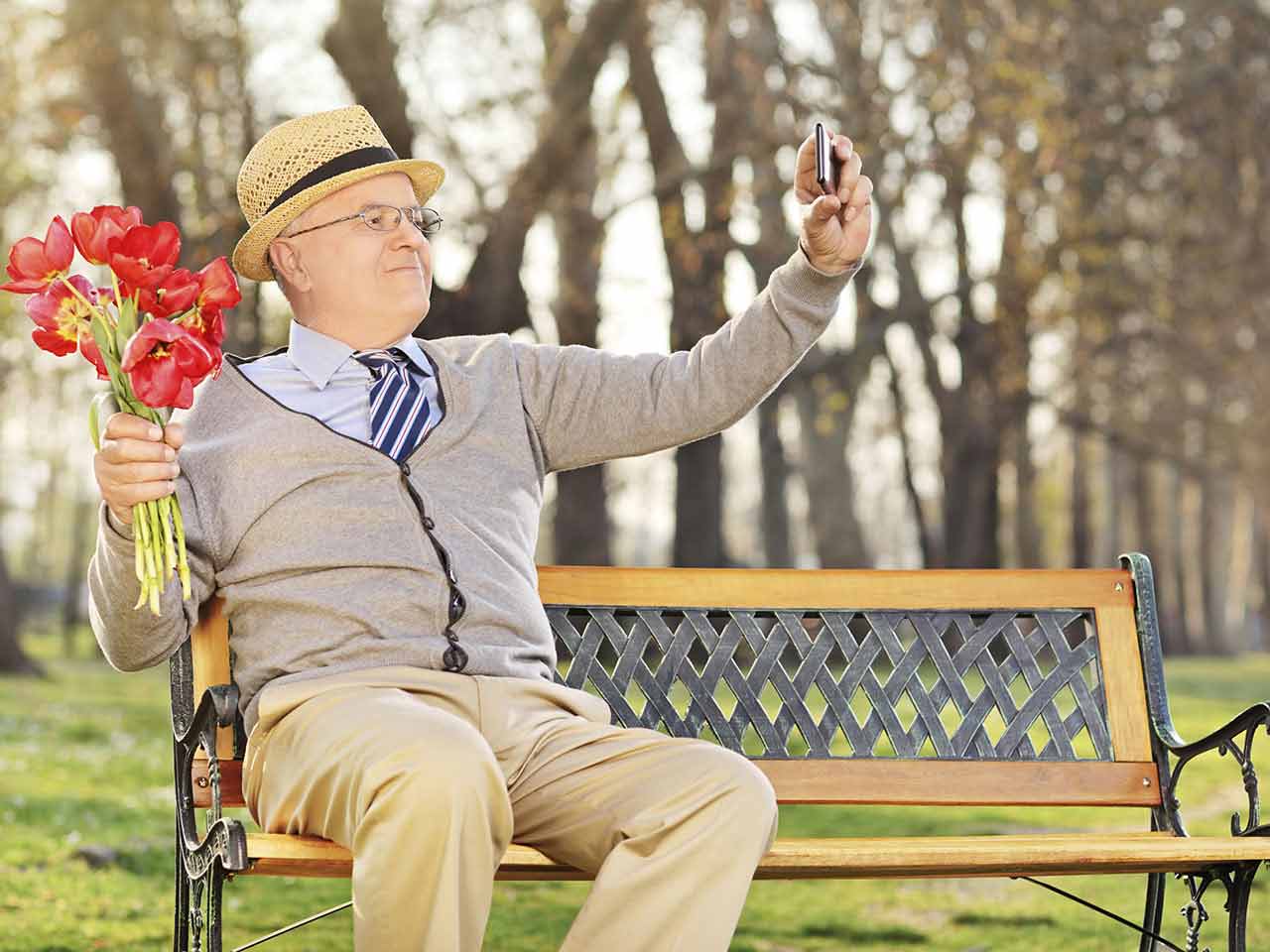 Senior gentleman sitting on bench with flowers wiating for a date 