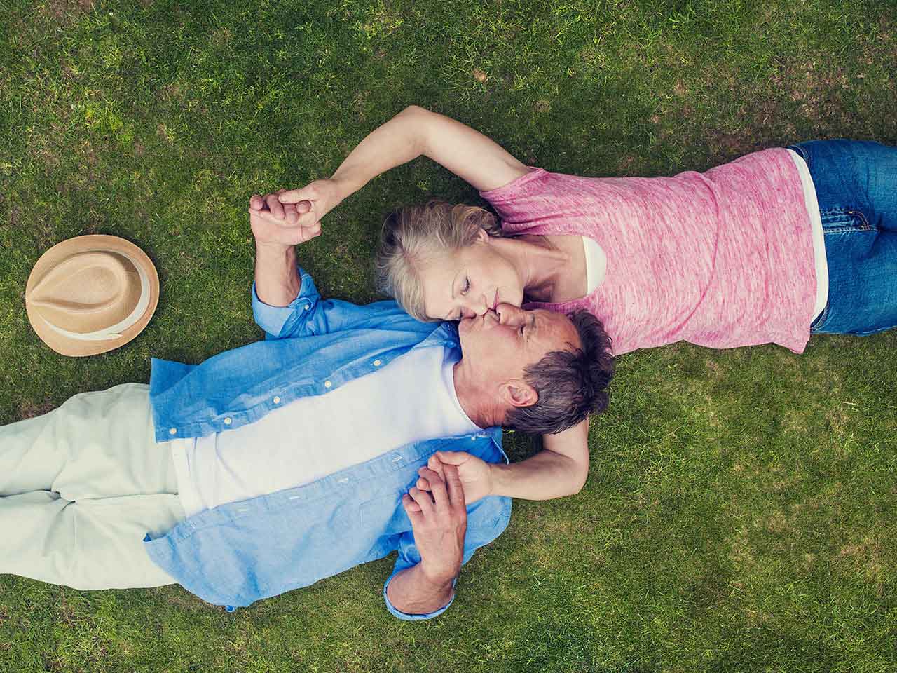 Mature couple lying on the grass embracing