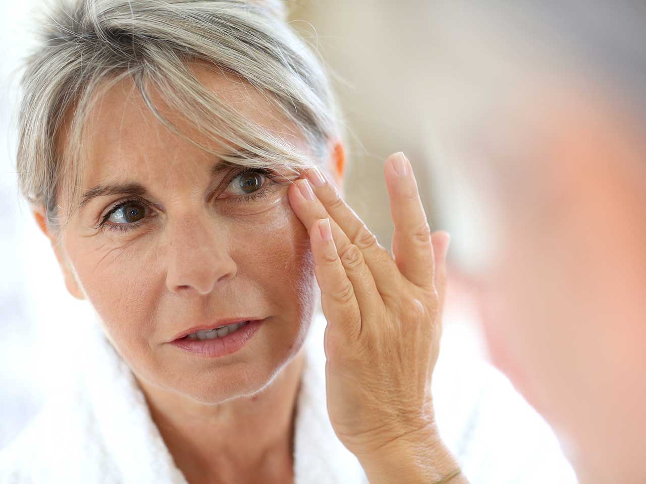 Mature woman applying moisturiser