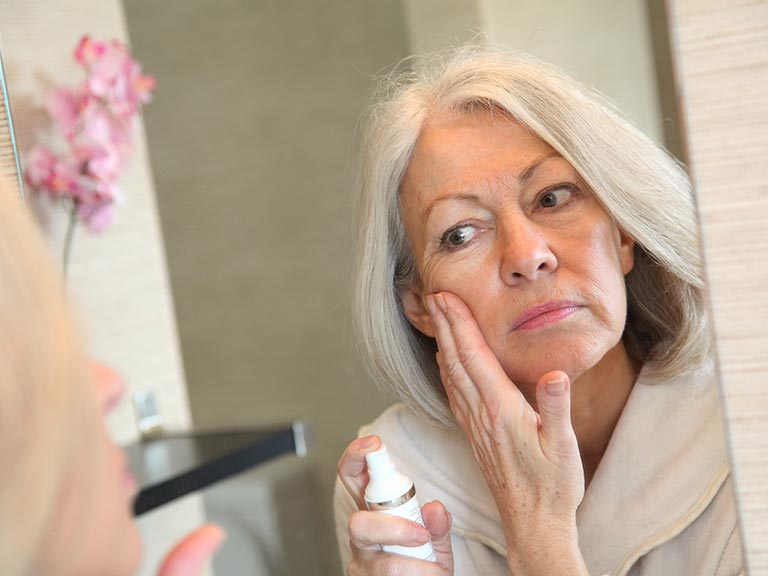 Senior woman applying moisturiser