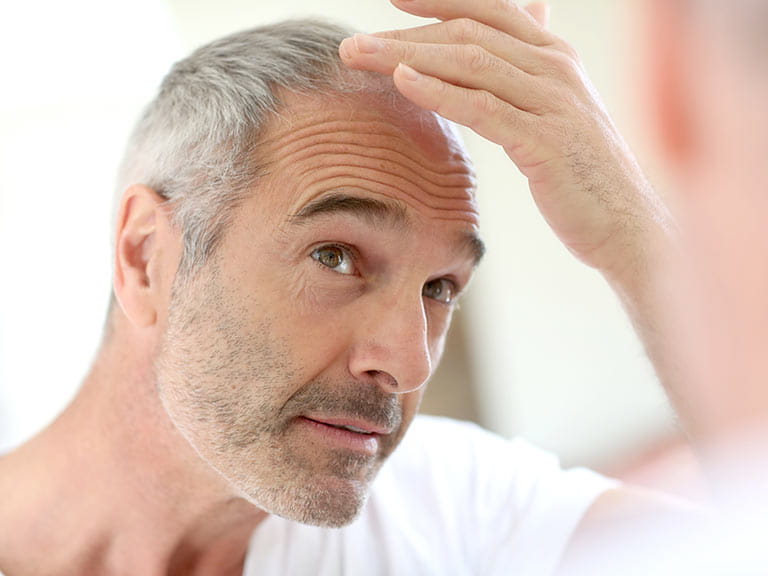 Mature man with receding hair looking in the mirror