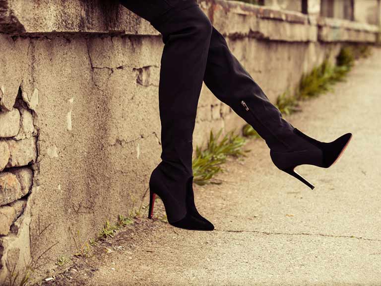 A woman wearing high heeled boots take a quick break