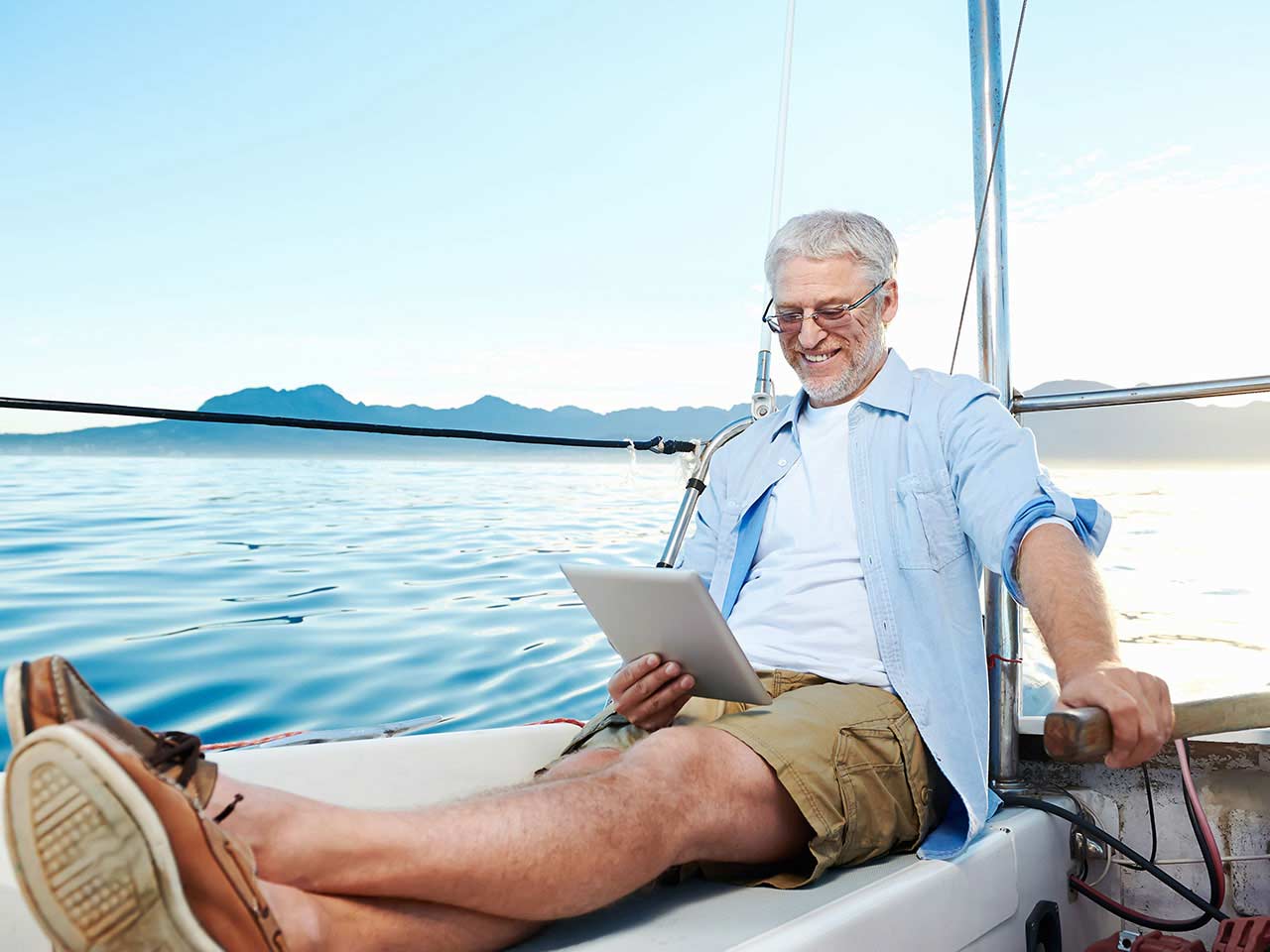 Happy man reading tablet on boat