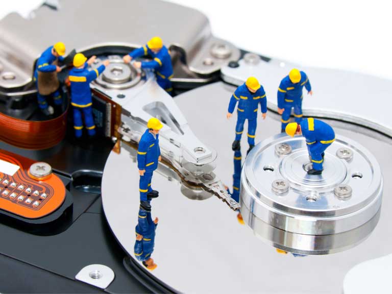 Group of small model figures mending a hard drive