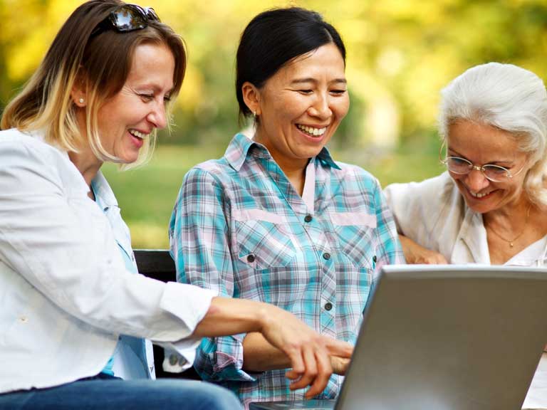 Three ladies looking at a laptop together