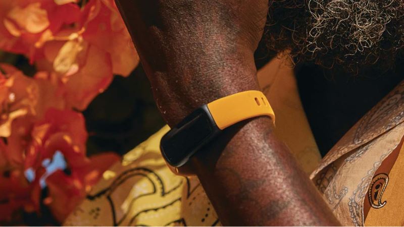 A bright orange fitbit fitness tracker on a man's arm