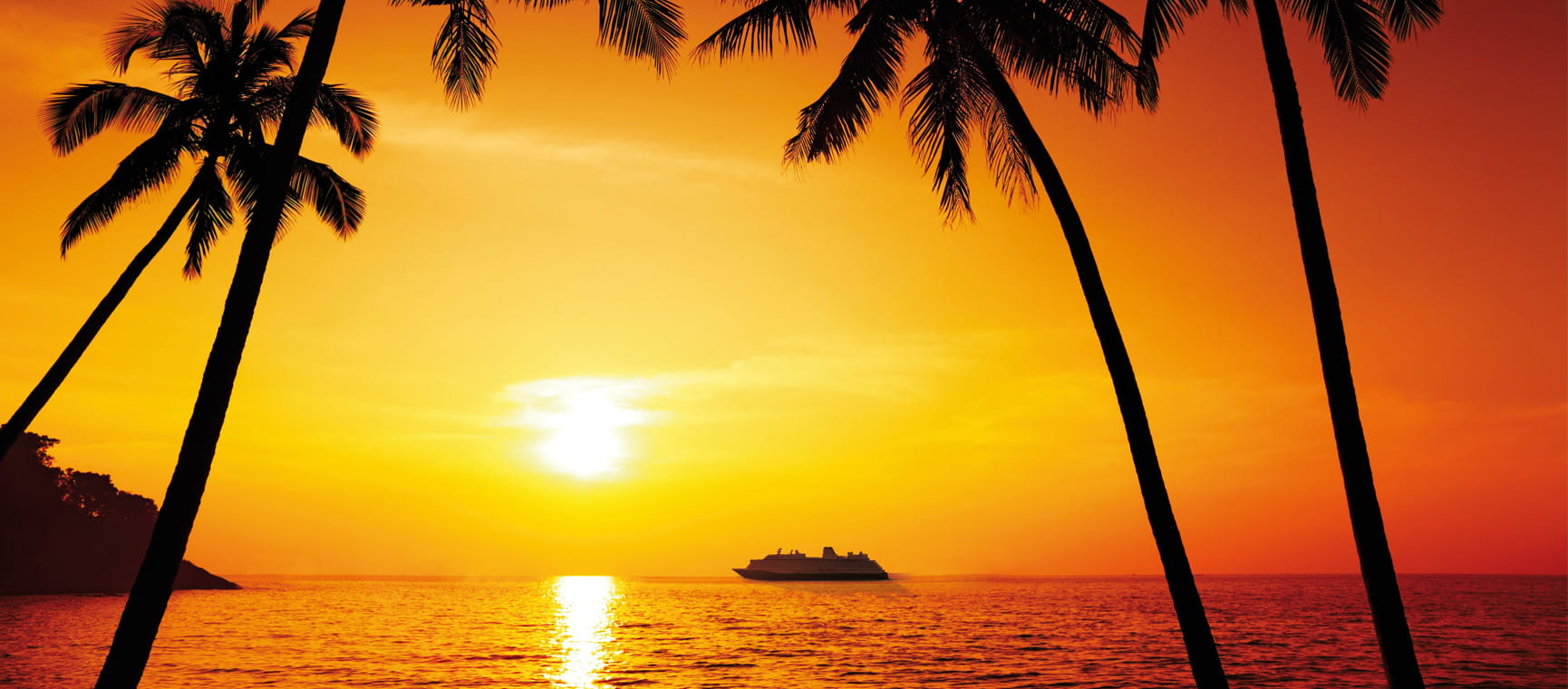 An orange sunset with palm trees over a bay with a cruise ship