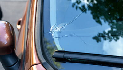 A large crack in the bottom corner of a car windscreen