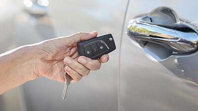 Close up of a woman's hand holding a car key next to the car door