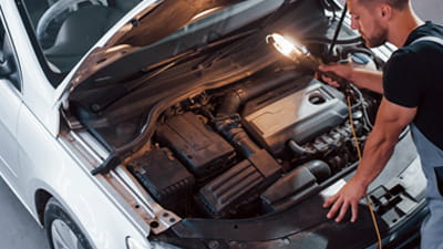 A man looking under the bonnet of a car in a garage