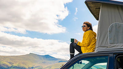 Woman sitting on campervan in the Brecon Beacons