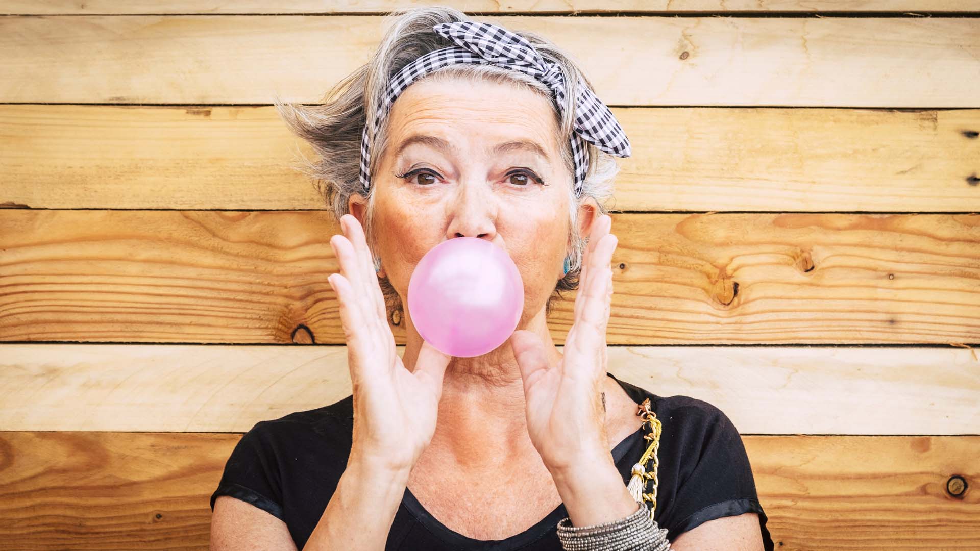 A woman blowing a bubble with pink bubblegum