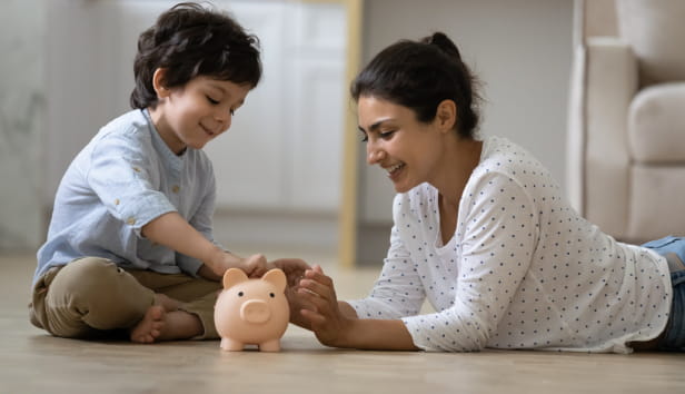 A mother and son adding money to a piggy bank