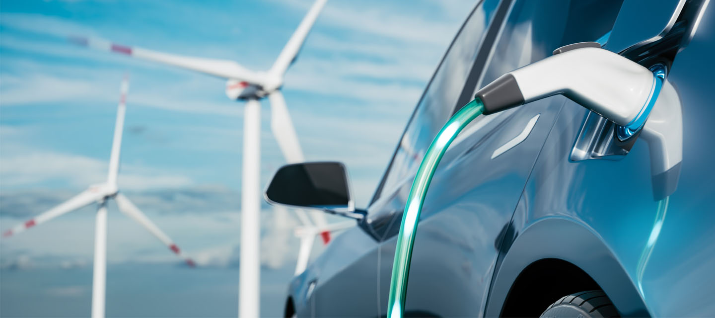 An electric car on charge near a wind farm