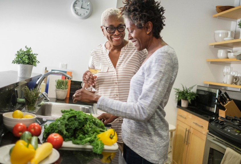 Two women stood chatting in the kitchen while preparing vegetables